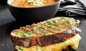 Grilled Cheddar and herb sandwich with a bowl of tomato soup